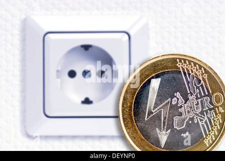 Una moneta in euro con un fulmine simbolo di potenza di fronte a una presa di alimentazione, immagine simbolica per l aumento dei costi di elettricità Foto Stock