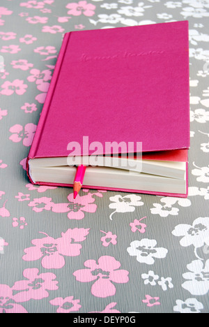 Chiuso libro rosa con penna come un segnalibro su disegno floreale Foto Stock