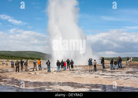 I turisti a guardare grande Geysir geyser che erutta, Haukadalur Valley, South Western Islanda. Foto Stock