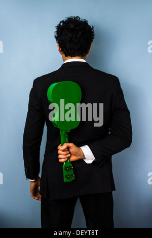 Vista posteriore di imprenditore tenendo un ukulele dietro la schiena Foto Stock