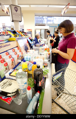 Una donna in attesa alla cassa supermercato Tesco, Fiveways, Birmingham, Regno Unito Foto Stock