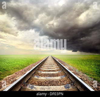 Linea ferroviaria nel campo e nuvole di tempesta Foto Stock