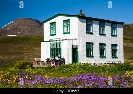 Legno o Cranesbill Bosco (Geranio Geranium sylvaticum), gli escursionisti seduto di fronte a una casa, villaggio di Hesteyri Foto Stock