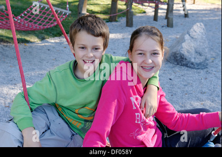 Un ragazzo e una ragazza seduta su un parco giochi, Schliersbergalm alp, vicino al lago di Schliersee, Alta Baviera, Baviera Foto Stock