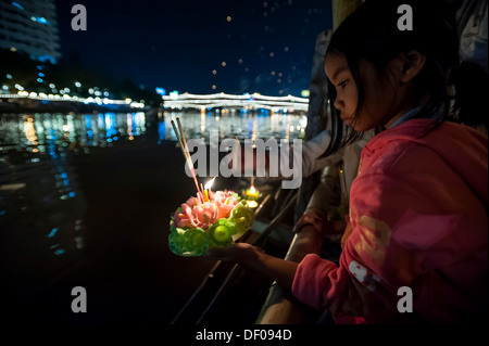 Ragazza giovane collocando un cerimoniale in zattera sul fiume, Loi o Loy Krathong Festival, Chiang Mai, Thailandia del Nord della Thailandia, Asia Foto Stock