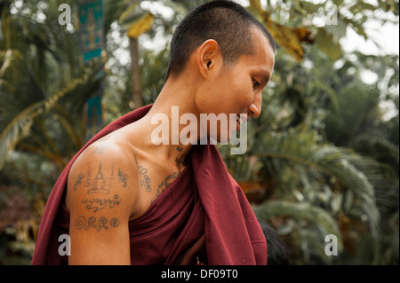 Sorridente monaco buddista con tatuaggi raccogliendo elemosine al mattino, ritratto, il tempio e il monastero di Wat Phra Archa Thong o Foto Stock