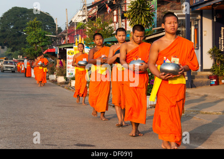 Mattina alms round, giovani monaci buddisti da un monastero scuola holding di accattonaggio bocce, Provincia di Sukhothai, Thailandia del Nord Foto Stock