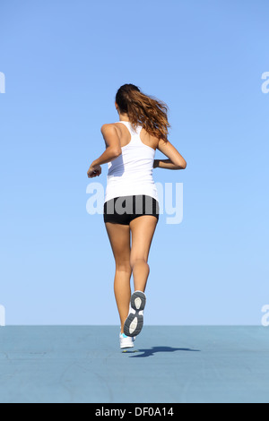 Vista posteriore di una donna per il fitness in esecuzione su blu con l'orizzonte in background Foto Stock