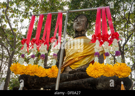 Seduto statua del Buddha, ghirlande floreali, buddista sacrifici, complesso tempio di Wat Khao Phnom Phloeng Foto Stock