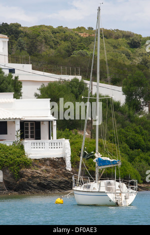 Barca a vela off una villa sulla costa nel porto naturale di Mao, Mahon Minorca, Minorca, Spagna, Europa Foto Stock