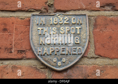 "Nel 1832 su questo posto non è successo niente". Le bizzarre parole in rilievo su una placca fissata al muro di mattoni di una vecchia casa in Bridport, Dorset, Inghilterra. Foto Stock