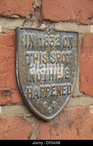 "Nel 1832 su questo posto non è successo niente". Le bizzarre parole in rilievo su una placca fissata al muro di mattoni di una vecchia casa in Bridport, Dorset, Inghilterra. Foto Stock