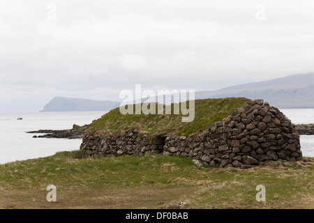 Vecchia casa di pietra con un tetto di erba sulla costa rocciosa, Kirkjubour, Streymoy Isola, Isole Faerøer, Danimarca, Atlantico del Nord Foto Stock