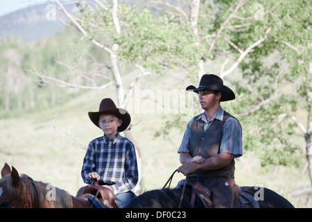 Cowboy western con il padre e il figlio corsa dei cavalli all'aperto nel Montana Foto Stock
