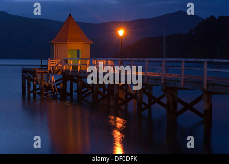Un molo e una lampada in Twilight, Akaroa, Penisola di Banks, regione di Canterbury, Isola del Sud, Nuova Zelanda Foto Stock