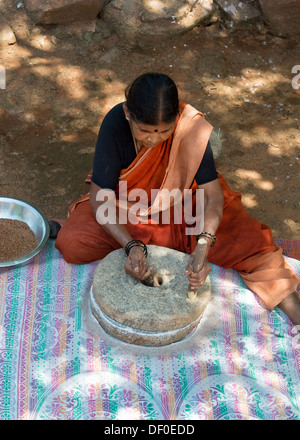 Rurale villaggio indiano donna utilizzando pietre Quern per macinare il miglio di dito seme / Ragi semi in Ragi farina. Andhra Pradesh. India Foto Stock