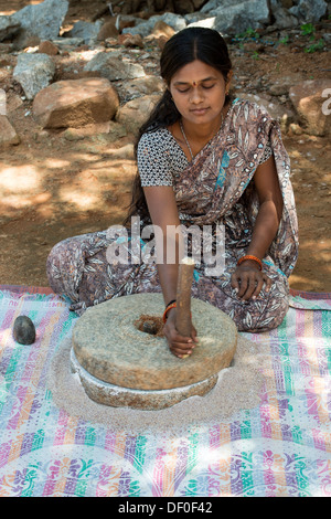 Rurale villaggio indiano donna utilizzando pietre Quern per macinare il miglio di dito seme / Ragi semi in Ragi farina. Andhra Pradesh. India Foto Stock