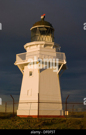 Waipapa Point Lighthouse nella luce della sera con nuvole scure sul retro, Otara, Fortrose, Southland, Nuova Zelanda Foto Stock