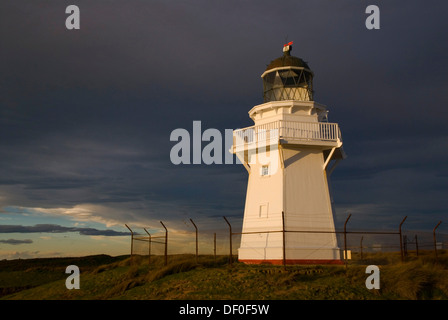 Waipapa Point Lighthouse nella luce della sera con nuvole scure sul retro, Otara, Fortrose, Southland, Nuova Zelanda Foto Stock