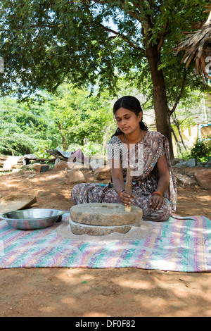 Rurale villaggio indiano donna utilizzando pietre Quern per macinare il miglio di dito seme / Ragi semi in Ragi farina. Andhra Pradesh. India Foto Stock