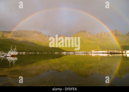 Un arcobaleno pieno oltre il mare di Norvegia vicino Grashopen e alcune barche da pesca riflessa fuori l'isola di Senja, Troms, Norvegia Foto Stock