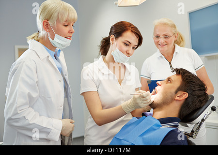 Assistente dentale tenendo approvazione prova con due dentisti Foto Stock