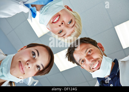 Dentista e team guardando verso il basso durante il trattamento sul paziente Foto Stock