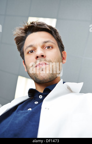 Ritratto di un giovane bello medico sorridente in un bianco camice Foto Stock