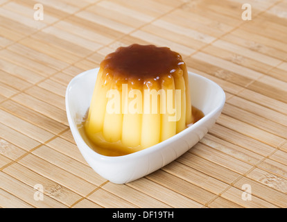 Caramello sformato di crema pasticcera in un recipiente su un sfondo di bambù Foto Stock