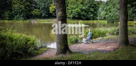 Un pescatore che pesca in Old Hall stagno a Thorndon Country Park in Essex. Foto Stock