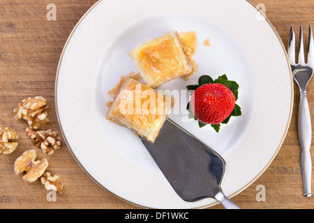Paio di pezzi di fatto in casa il baklava pronte per essere servite con in acciaio inox spatola su bambù vecchio tagliere lungo wit Foto Stock