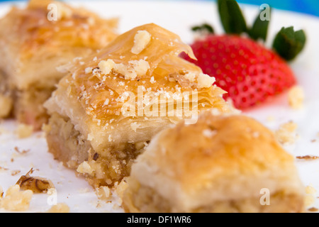 Tre pezzi di colore dorato baklava guarnita con noci e fragola, macro shot Foto Stock