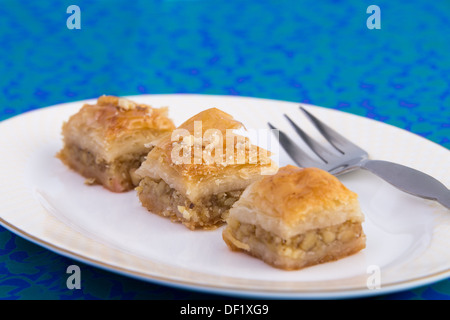 Tre pezzi di colore dorato il baklava è servita a forma ovale piastra sul verde e blu tovaglia Foto Stock