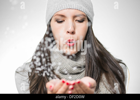 Piuttosto giovane donna in inverno la moda con lunghi brunette capelli fiocchi di neve di soffiaggio o di polvere magica Foto Stock