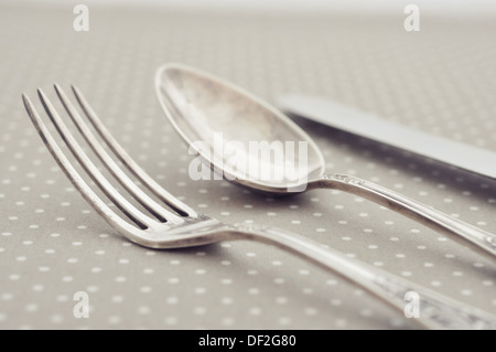 Forchetta, cucchiaio e il coltello sulla luce polka dot sfondo. Foto Stock