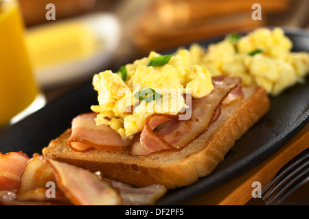 Frittura di pancetta e uova strapazzate su pane tostato (messa a fuoco selettiva, messa a fuoco sulla parte anteriore del lo scalogno nella parte anteriore) Foto Stock