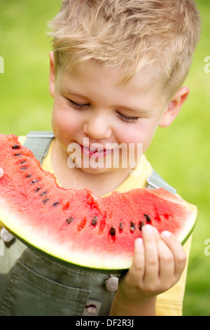 Ritratto di un ragazzo di mangiare una fetta di cocomero Foto Stock