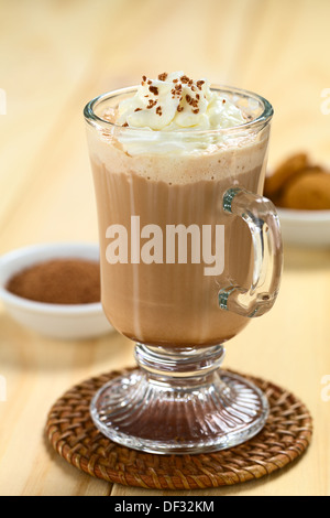 Cioccolata calda con panna montata e scaglie di cioccolato sulla parte superiore, con la polvere di cacao e i cookie nel retro Foto Stock