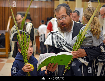 Una religiosa ebraica padre e figlio di trattenimento di un etrog e lulav al mattino i servizi di preghiera in Crown Heights, Brooklyn, New York Foto Stock