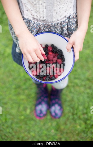 Ragazza con una ciotola di lamponi freschi e more Foto Stock