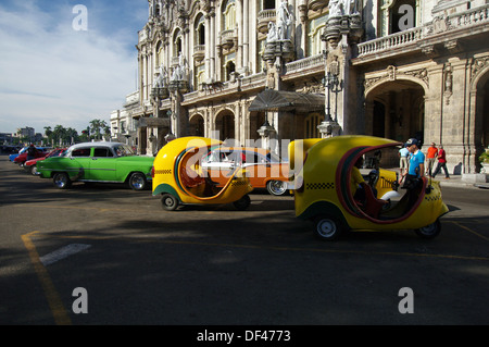 Cocotaxis e auto d'epoca parcheggiato di fronte al grande teatro di Havana - Havana, Cuba Foto Stock