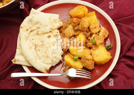 Goa di pollo e le patate e vindaloo curry, cotti in un aceto e salsa di spezie e servito con una fetta di pane piatto Foto Stock