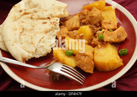 Goa di pollo e le patate e vindaloo curry, cotti in un aceto e salsa di spezie e servito con una fetta di pane piatto Foto Stock