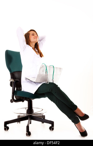 Medico donna lavorando sul suo computer portatile e lo stiramento al suo posto di lavoro contro uno sfondo bianco Foto Stock