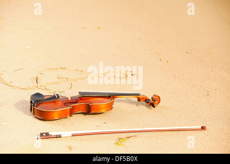 Violino e g chiave di violino la forma sulla spiaggia sabbiosa. Amore del concetto di musica Foto Stock