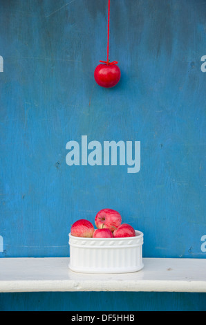 Appendere rosso apple sulla stringa e vaso bianco con frutti. Vita sana nozione Foto Stock