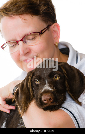 Donna felice e tedesco puntatore wirehaired puppy, dodici settimane, sfondo bianco formato verticale Foto Stock