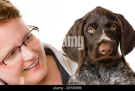 Donna felice e tedesco puntatore wirehaired puppy, dodici settimane, sfondo bianco formato con orizzonte di riferimento Foto Stock