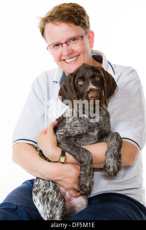 Donna felice e tedesco puntatore wirehaired puppy, dodici settimane, sfondo bianco formato verticale Foto Stock