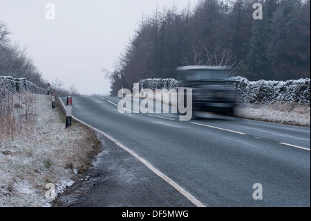 Movimento sfocate di Land Rover Defender 4x4 viaggia & essendo azionato sul vicolo del paese sul freddo, frosty ghiacciato, Winter's day - West Yorkshire, Inghilterra, Regno Unito. Foto Stock